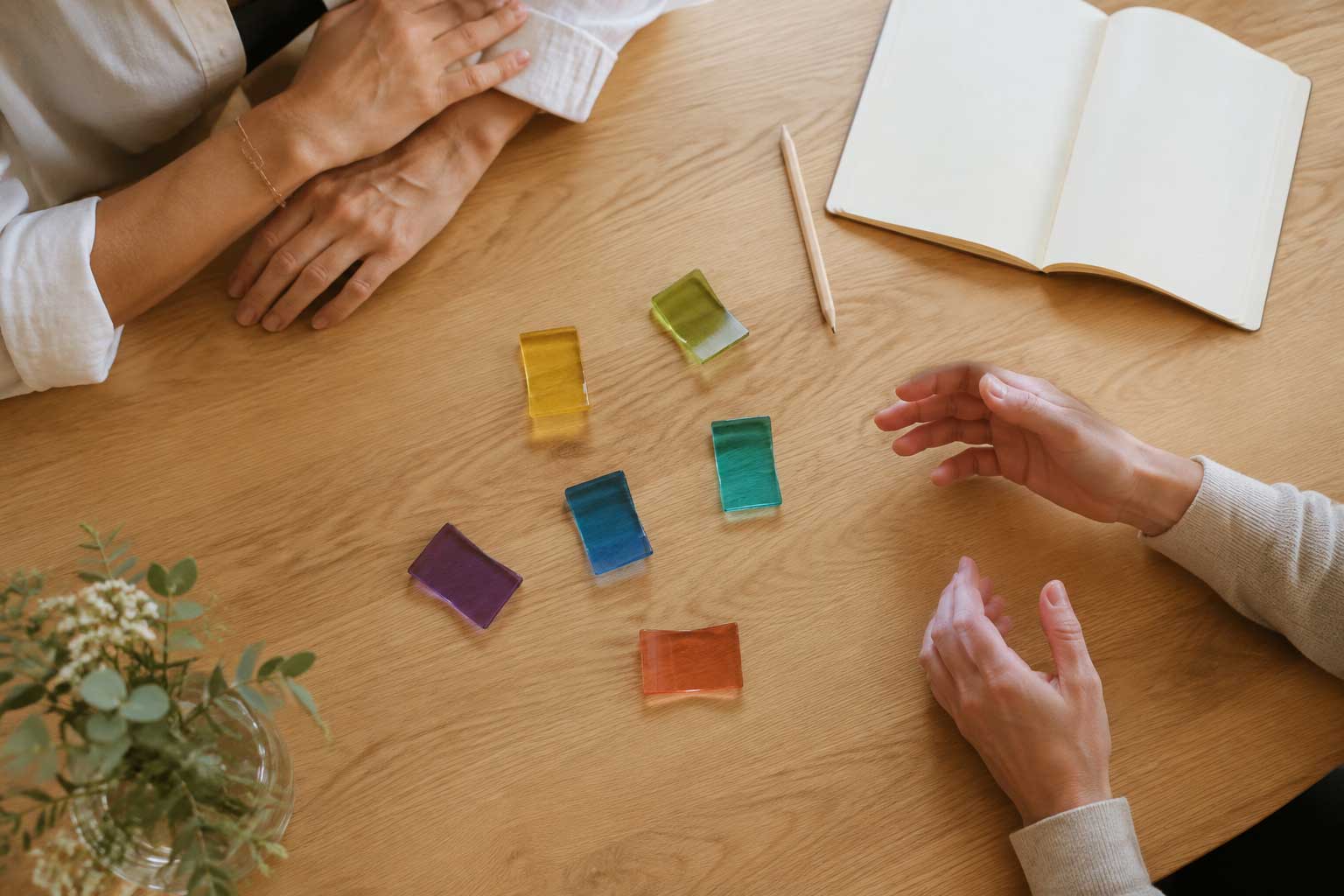 Zwei Menschen sprechen an einem Tisch über verschiedene farbige Glasflächen