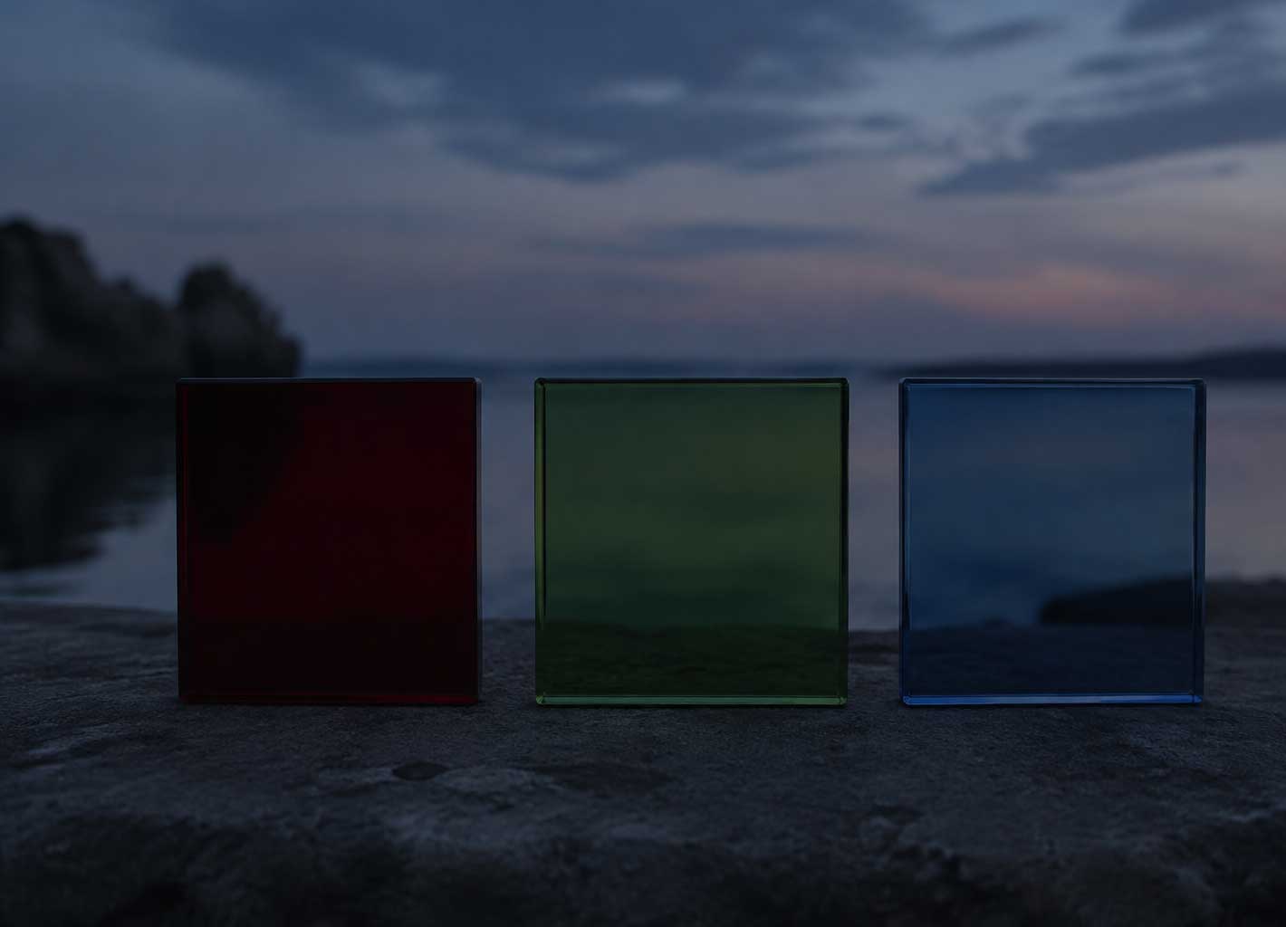 Rote, grüne und blaue transparente Glasflächen in der Dämmerung, wobei Rot bereits dunkler wirkt