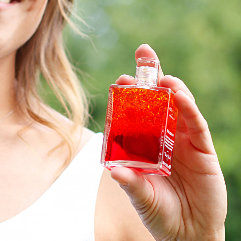 Aura-Soma Equlibriumflasche B5 Eine lächelnde Frau hält die geschüttelte Aura-Soma-Flasche B5 in der Hand.